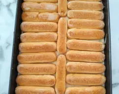 Step <p>.</p><p>Remojamos brevemente la mitad de los bizcochos de soletilla en el zumo de naranja, lo justo para que se empapen sin romperse y vamos colocándolos en el fondo de una fuente rectangular (23 cm x 15 cm x 8 cm). Extendemos la mitad de la mezcla del mascarpone sobre la base de bizcochos. Remojamos los bizcochos restantes, los colocamos sobre la crema y los cubrimos con el resto de la mezcla de mascarpone. Cubrimos con film transparente el molde y lo tenemos que dejar en el frigorífico mínimo de 5 horas. Espolvoreamos con la piel de naranja.</p> illustration